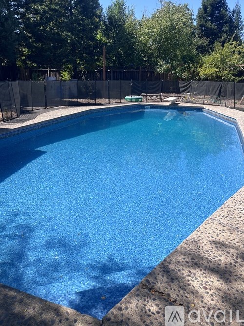 A blue swimming pool surrounded by a black fence.