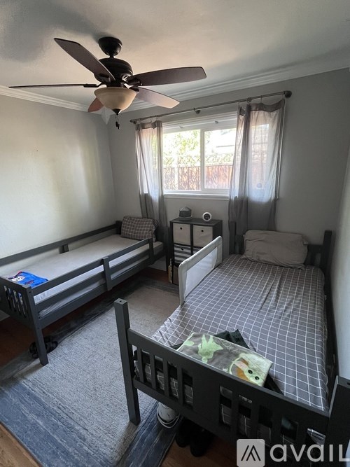 A bedroom with a bed, a fan, and a window with curtains.
