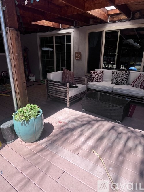 A patio with a couch, table, and potted plant.