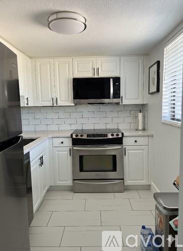 A kitchen with white cabinets and a black fridge.