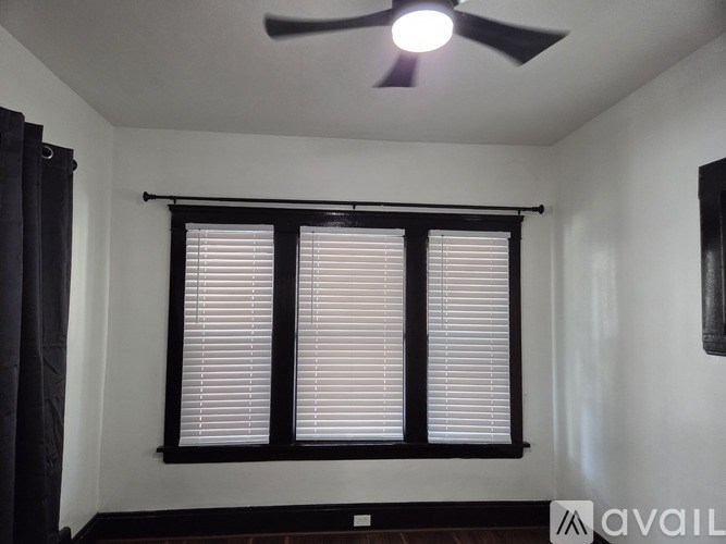 A room with a ceiling fan and a window with blinds.
