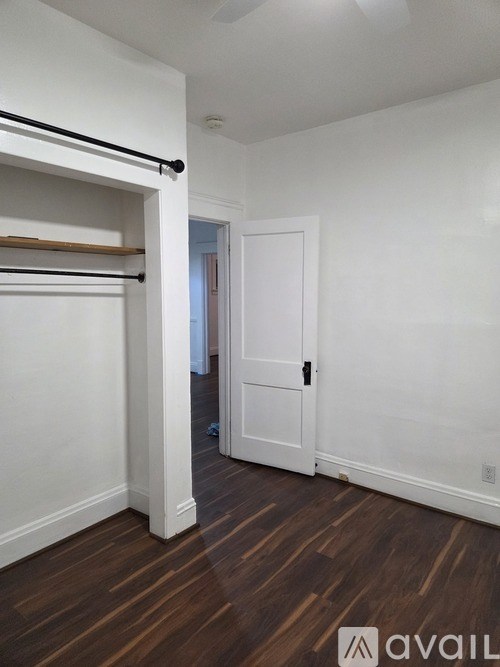 A room with a white door and a white wall with a wooden floor.