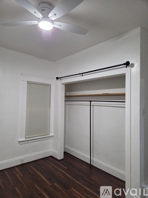 A room with a ceiling fan and a closet with a rod.