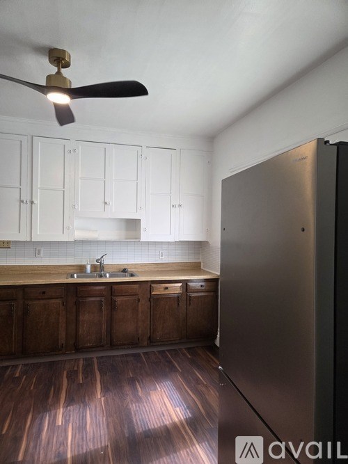 A kitchen with a ceiling fan and wooden cabinets.