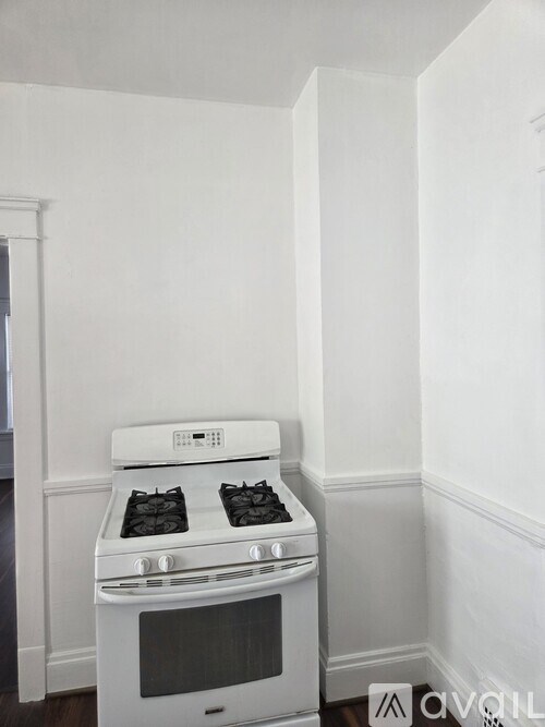 A white oven with a stove top and oven door is in a room with white walls.