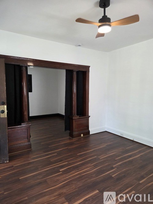 A room with a ceiling fan and wooden floors.