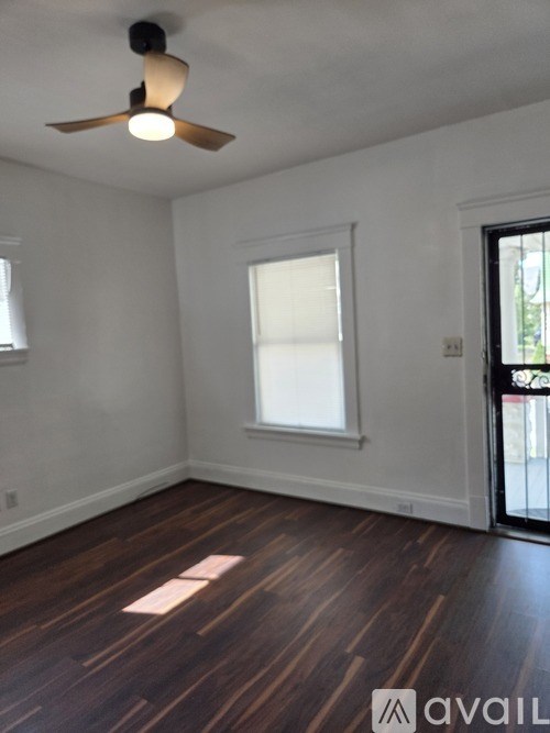 A room with a ceiling fan and wooden flooring.