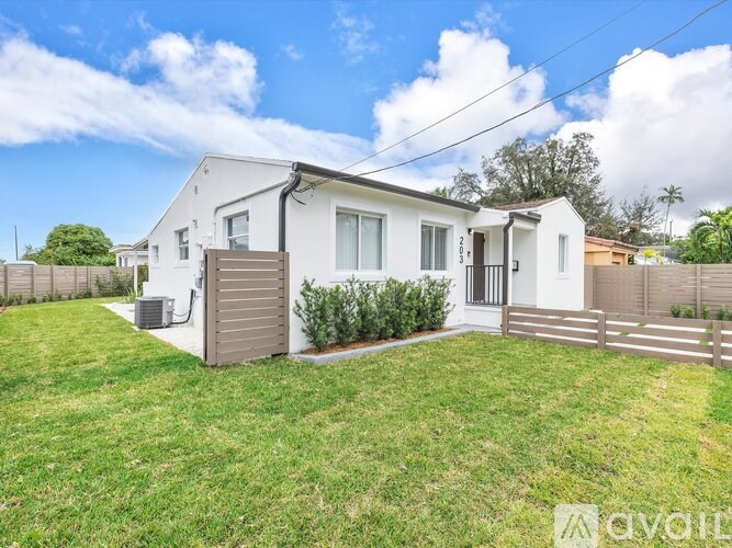 A white house with a brown fence and green grass in front.