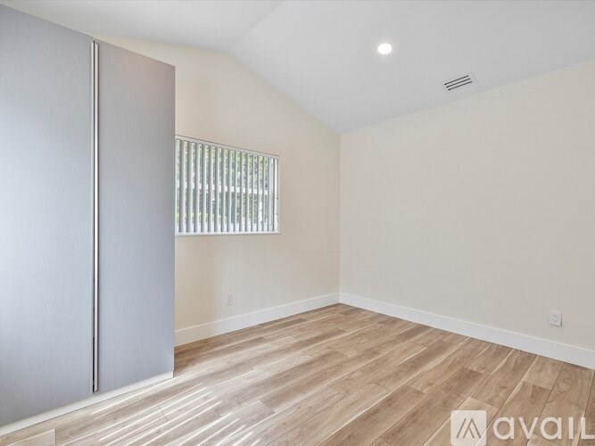 A room with a wooden floor and a grey door.