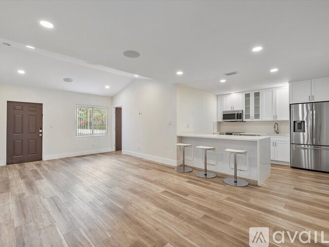 A spacious kitchen with white cabinets and a wooden floor.