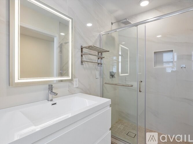 A white bathroom with a glass shower stall and a white sink.