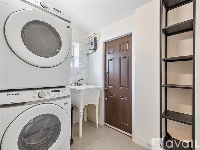 A white washing machine and dryer are stacked on top of each other in a small laundry room.