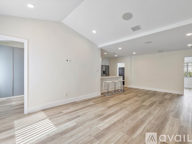 A spacious room with wooden flooring and a bar area.