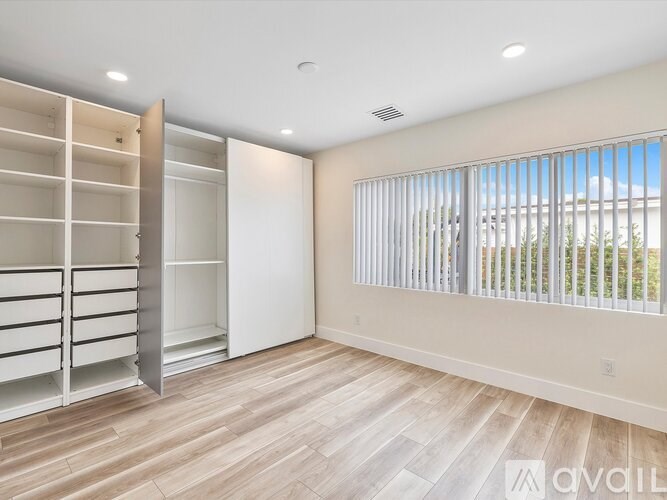 A spacious room with a built-in closet and a window with blinds.