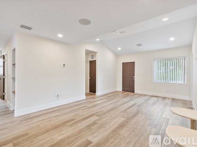 A spacious room with wooden flooring and white walls.