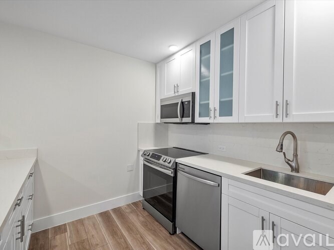 A kitchen with white cabinets and a wooden floor.