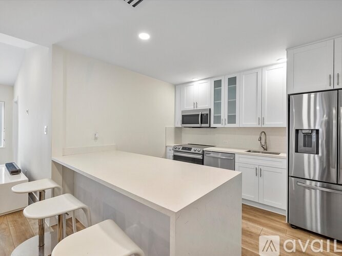 A modern kitchen with white cabinets and stainless steel appliances.