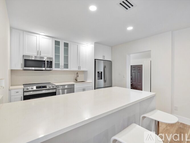 A modern kitchen with white cabinets and appliances.