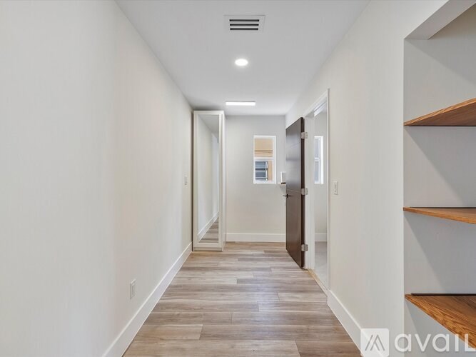 A long hallway with wood floors and white walls.