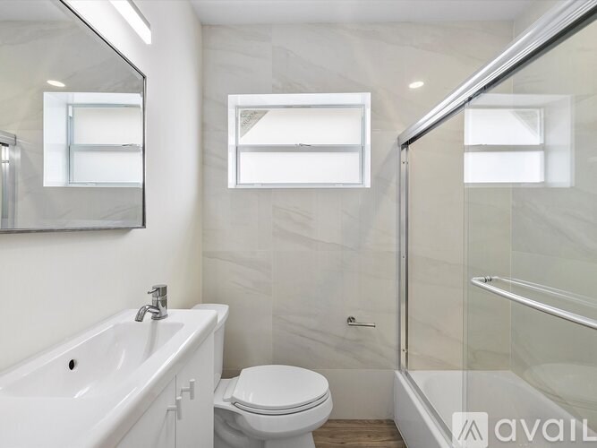 A bathroom with a white toilet, sink, and mirror.