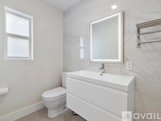 A white bathroom with a toilet, sink, and mirror.