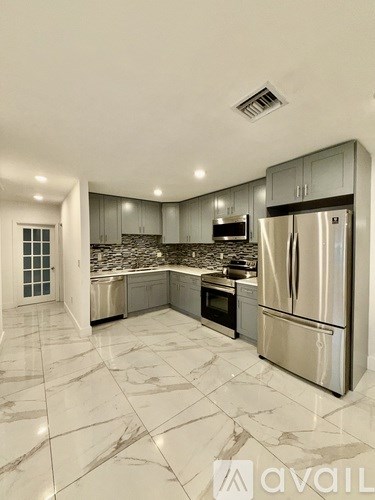 A kitchen with a marble floor and stainless steel appliances.