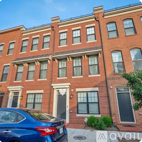 A blue car is parked in front of a red brick building.