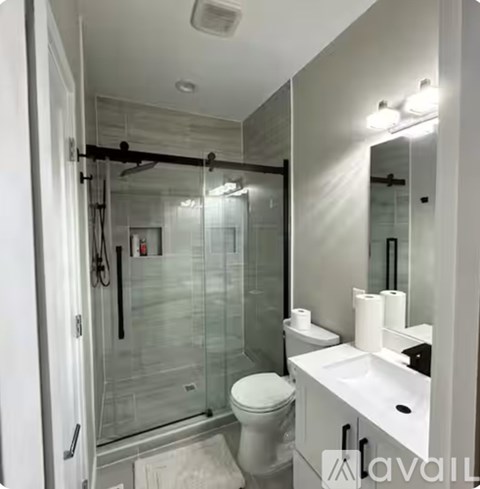 A white toilet sits in a modern bathroom with a glass shower.