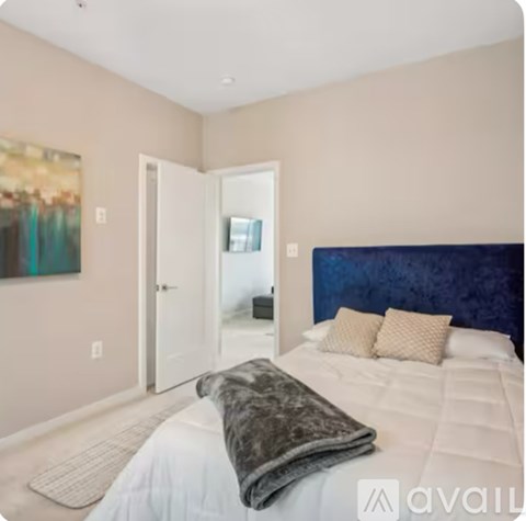 A bedroom with a large bed and a painting on the wall.