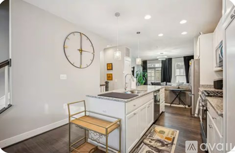 A kitchen with a white fridge, a clock on the wall, and a table with a bench.