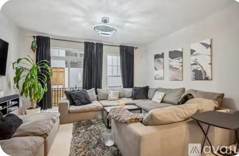 A living room with a large couch, a coffee table, and a potted plant.