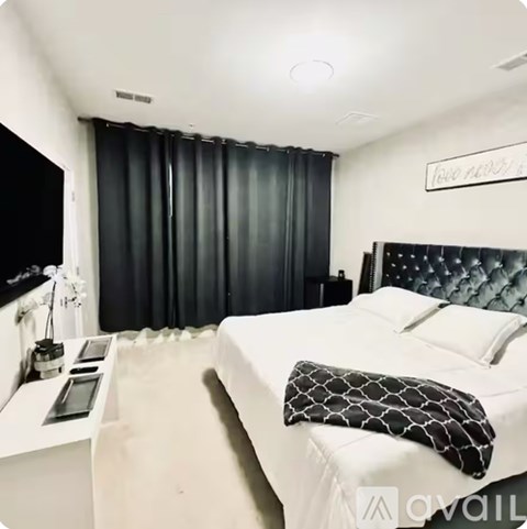 A bedroom with a white bed and a black and white pillow.