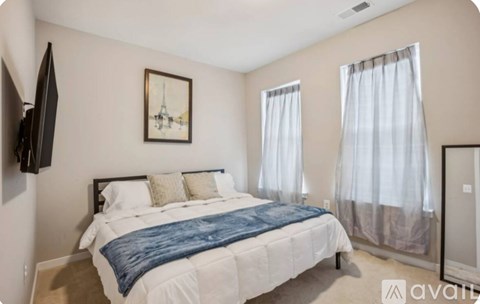 A bedroom with a bed, a television, and a painting on the wall.