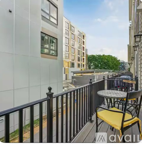 A balcony with a table and chairs overlooks a city street.