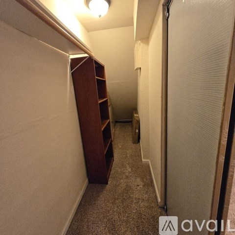 A hallway with a wooden shelf on the left and a white door on the right.