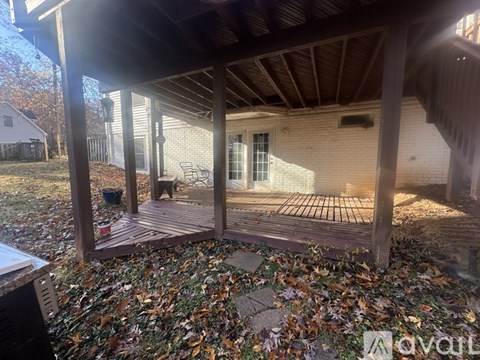 A wooden deck with a table and chairs is surrounded by fallen leaves.