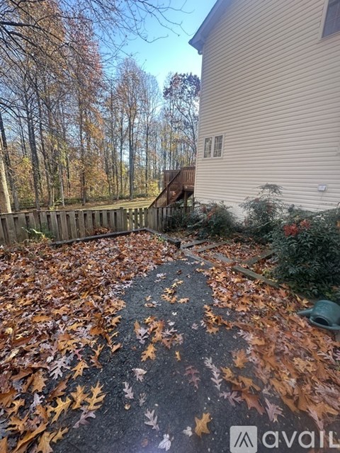 A driveway covered in fallen leaves leading to a house.