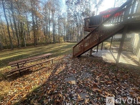 A wooden deck with a bench and a staircase leading to a house.