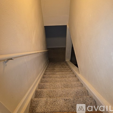 A staircase with a carpeted runner and white walls.