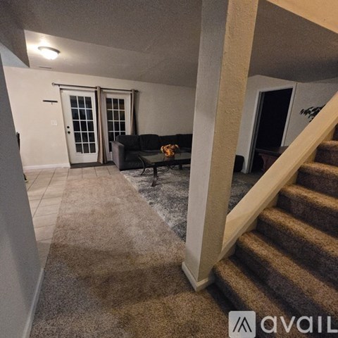 A living room with a couch, a coffee table, and a staircase.