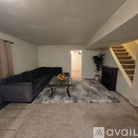 A living room with a grey couch and a glass coffee table.