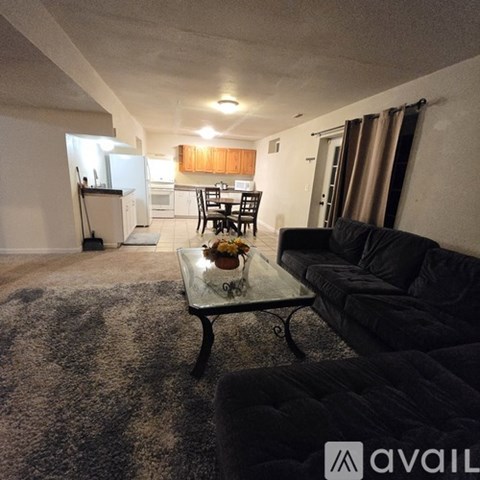 A living room with a black couch and a glass coffee table.