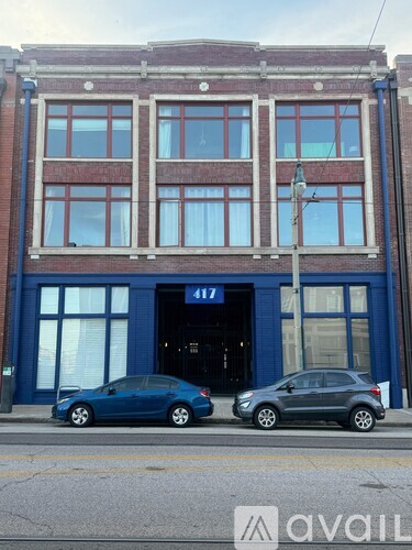 Two cars are parked in front of a building with the number 417 on it.