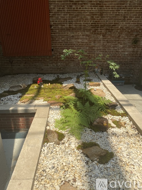A garden with a red brick wall and a gravel path.