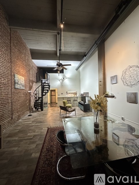 A modern living room with a glass table and a spiral staircase.
