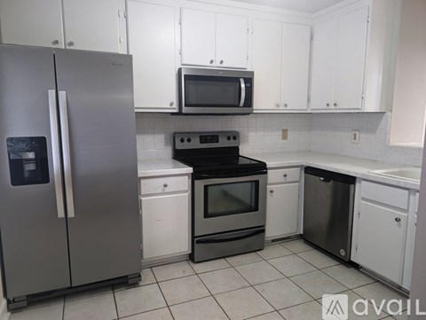 A kitchen with white cabinets and a stainless steel refrigerator.