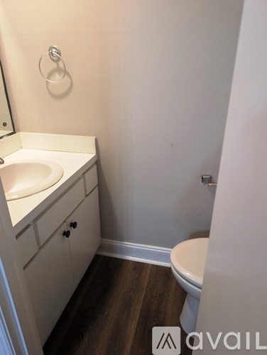 A small bathroom with a toilet, sink, and wooden floor.