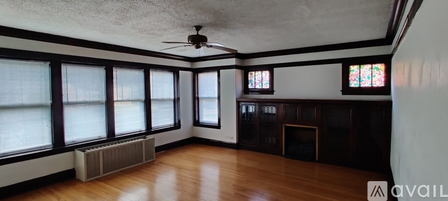 A room with a ceiling fan and large windows.