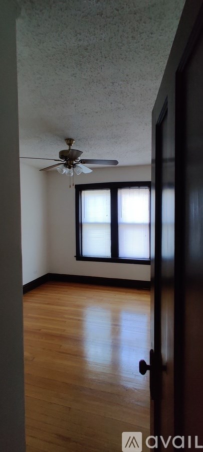 A room with a ceiling fan and wooden flooring.