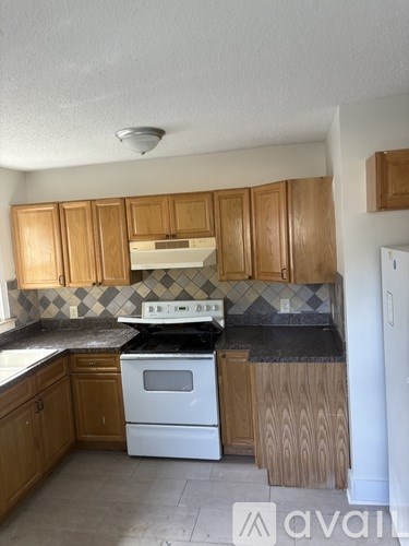 A kitchen with wooden cabinets and a white stove top oven.